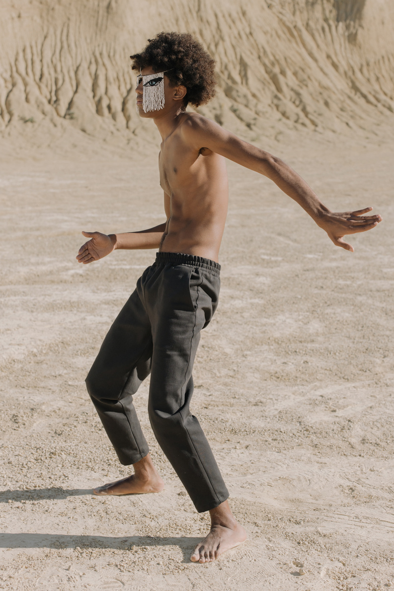 Topless Man in Black Pants Walking on White Sand